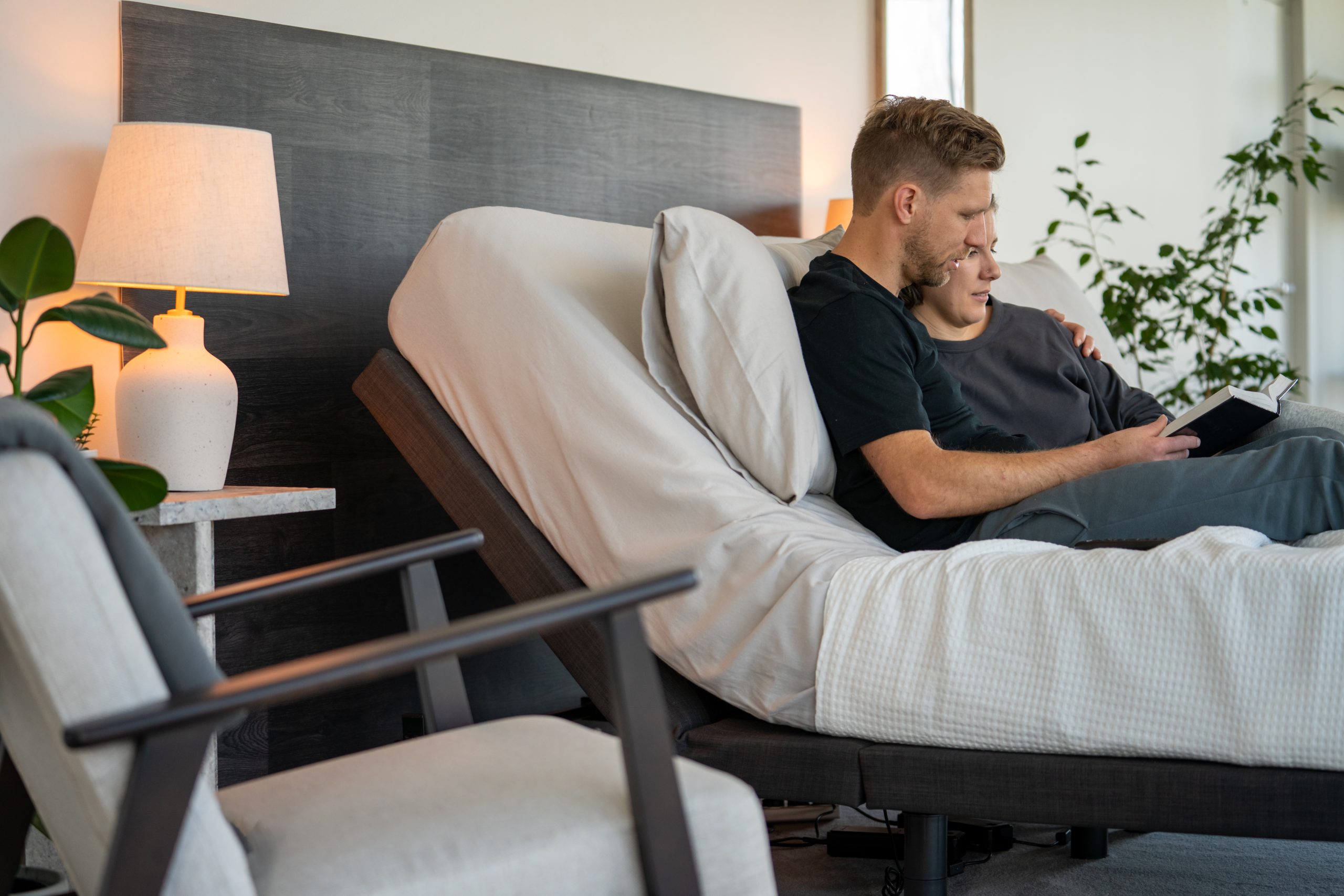 A couple comfortably reading in an adjustable bed, demonstrating how to achieve ideal positioning when learning how to choose a mattress and base system.