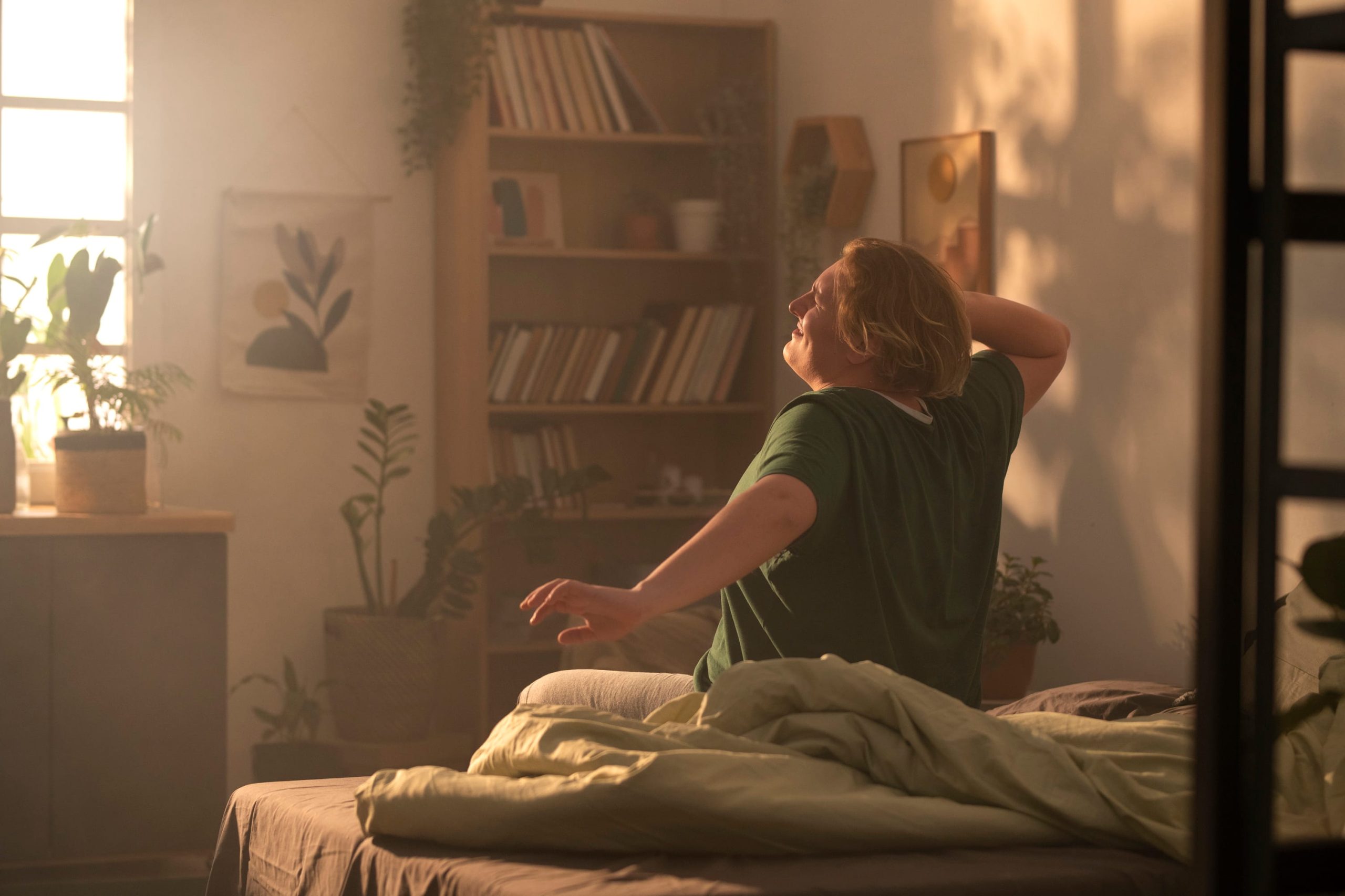 Person stretching in bed while bathed in morning sunlight, representing healthy sleep routine new year resolutions ideas